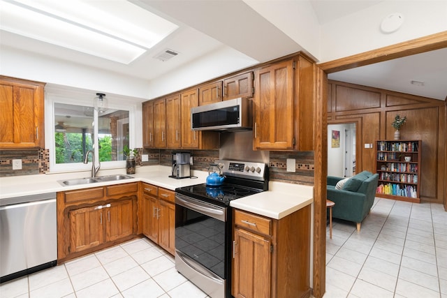 kitchen with stainless steel appliances, a sink, tasteful backsplash, and light tile patterned floors