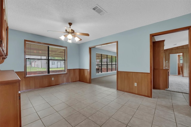 23010 County Road 3313, Chandler, TX 75758 - empty room featuring wooden walls, a wainscoted wall, a textured ceiling, a ceiling fan, and light tile patterned floors