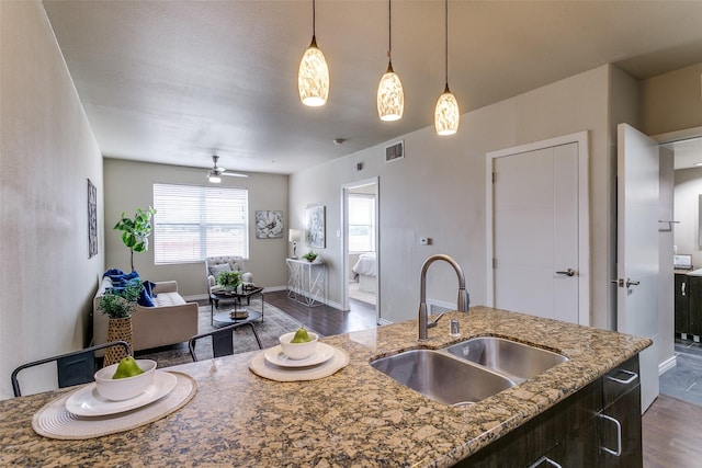 kitchen with a sink, dark wood-style floors, open floor plan, a ceiling fan, and decorative light fixtures