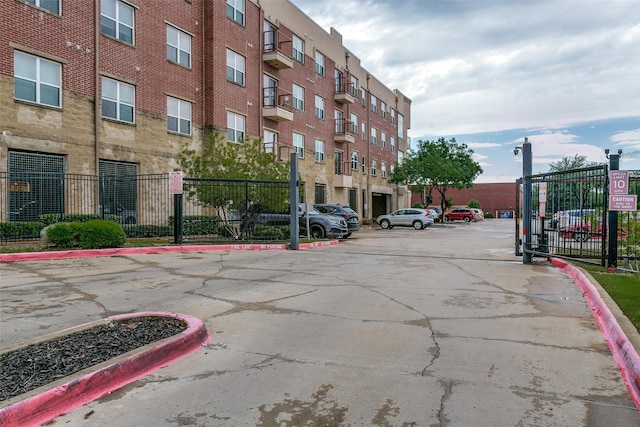 view of asphalt street featuring curbs, a gated entry, and street lighting