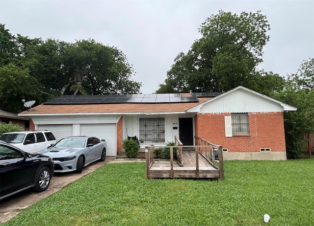 ranch-style home with brick siding, roof mounted solar panels, a garage, and a front yard