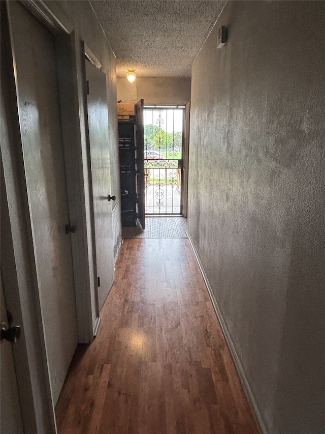 hallway featuring wood finished floors and a textured ceiling