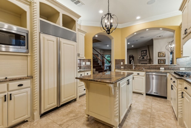 5957 Aberdeen Pl, Frisco, TX 75034 - kitchen featuring built in appliances, decorative backsplash, a center island, ornamental molding, and arched walkways