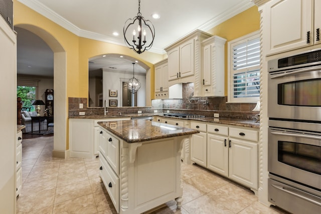 5957 Aberdeen Pl, Frisco, TX 75034 - kitchen featuring appliances with stainless steel finishes, a chandelier, a warming drawer, tasteful backsplash, and arched walkways