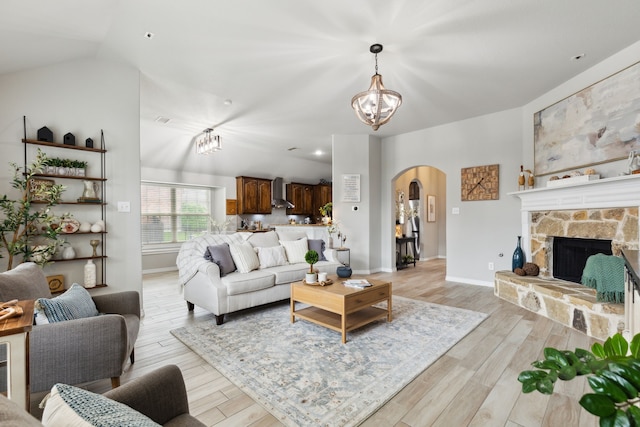 9529 Cholla Cactus Trl, Fort Worth, TX 76177 - living area featuring arched walkways, a chandelier, light wood-style floors, vaulted ceiling, and a fireplace
