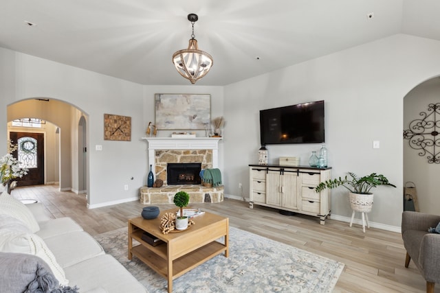 9529 Cholla Cactus Trl, Fort Worth, TX 76177 - living room featuring arched walkways, light wood finished floors, a chandelier, a fireplace, and lofted ceiling