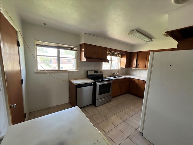 604 E 5th St, Weatherford, TX 76086 - kitchen featuring appliances with stainless steel finishes, light countertops, light tile patterned floors, and a sink