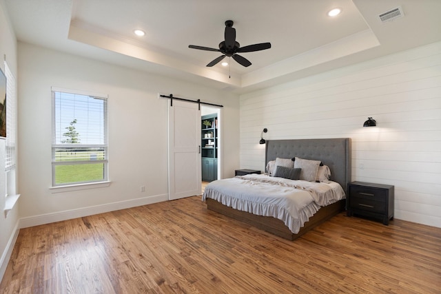109 Old Decatur Rd, Decatur, TX 76234 - bedroom featuring a tray ceiling, a barn door, wood finished floors, recessed lighting, and baseboards