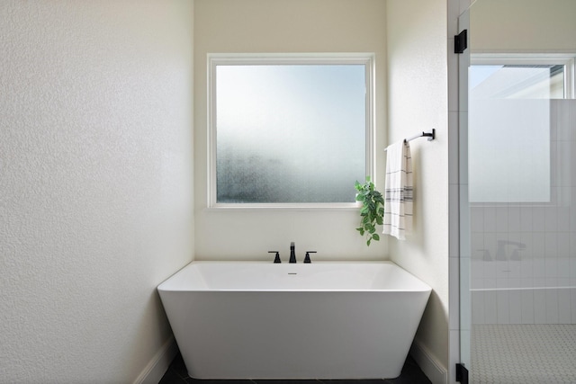 109 Old Decatur Rd, Decatur, TX 76234 - bathroom with healthy amount of natural light, a textured wall, a soaking tub, tiled shower, and baseboards