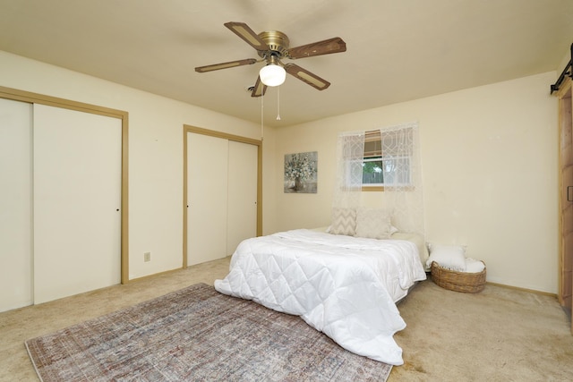 bedroom with two closets, carpet, and ceiling fan