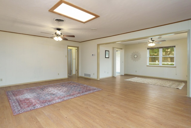 empty room featuring ceiling fan, wood finished floors, crown molding, and baseboards
