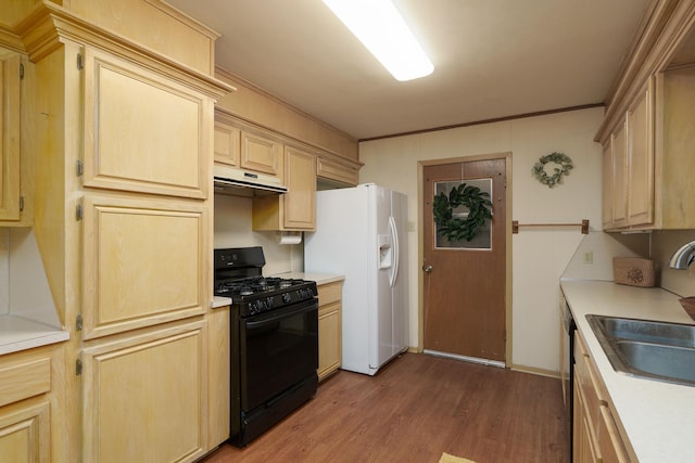 kitchen with black gas stove, under cabinet range hood, a sink, wood finished floors, and white fridge with ice dispenser