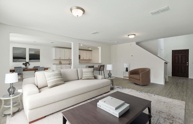 living area with light wood-type flooring, stairs, and baseboards