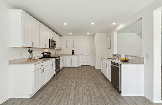 kitchen with appliances with stainless steel finishes, a sink, light wood finished floors, and recessed lighting