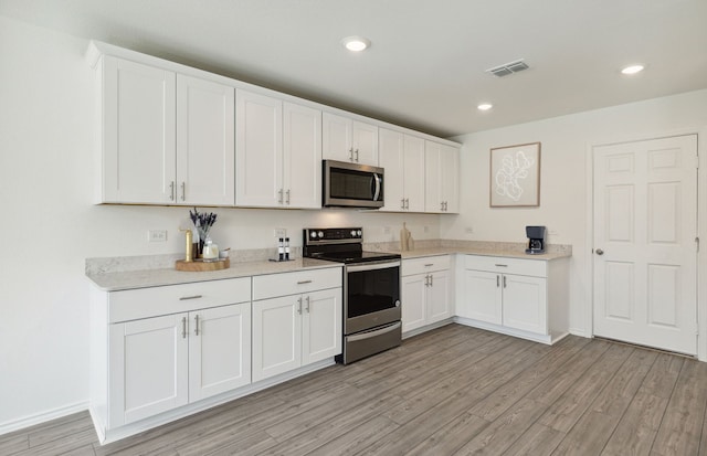 kitchen featuring stainless steel appliances, light wood-style flooring, light countertops, white cabinets, and recessed lighting