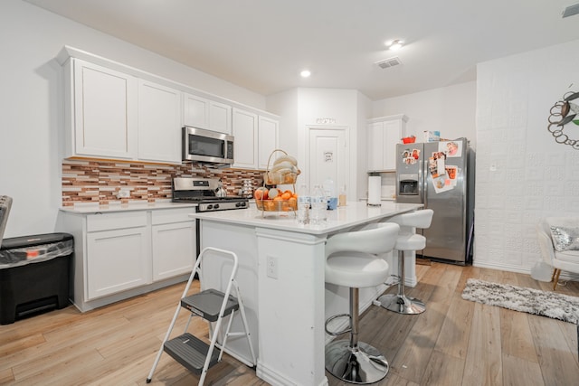 1034 Manuel Dr, Fate, TX 75087 - kitchen featuring appliances with stainless steel finishes, a breakfast bar, light wood-type flooring, white cabinets, and recessed lighting