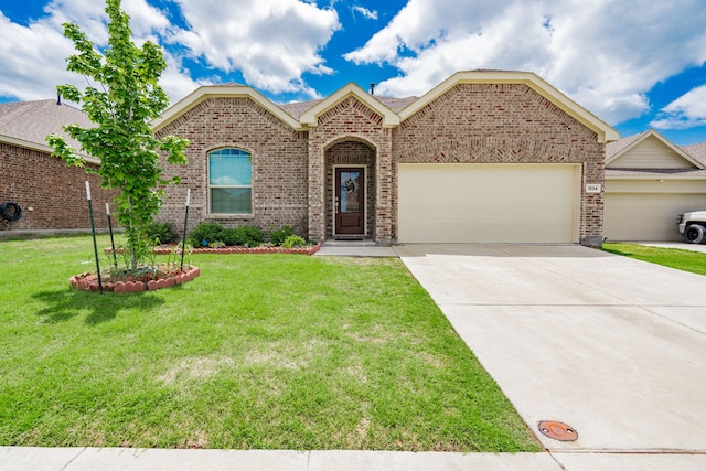 1034 Manuel Dr, Fate, TX 75087 - view of front of property with brick siding, an attached garage, concrete driveway, and a front yard