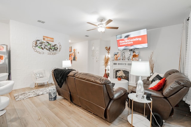 1034 Manuel Dr, Fate, TX 75087 - living area featuring light wood-style floors, ceiling fan, and a fireplace with raised hearth
