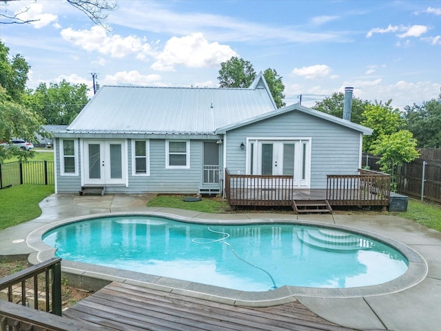 back of property featuring french doors, a wooden deck, a fenced backyard, and metal roof