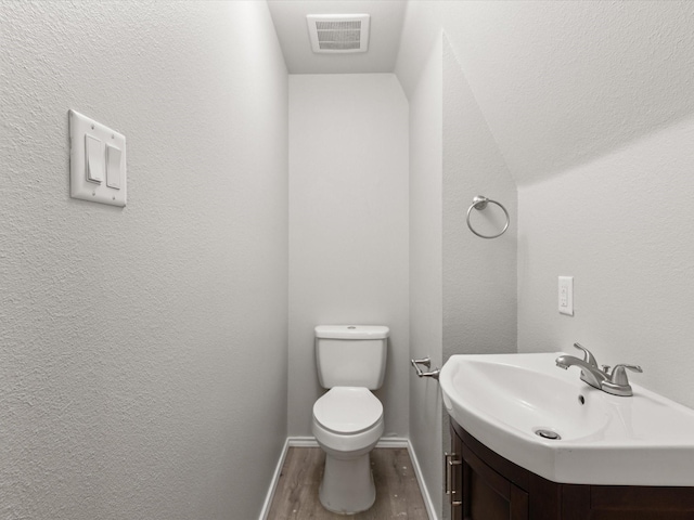 bathroom with wood finished floors, toilet, vanity, and baseboards