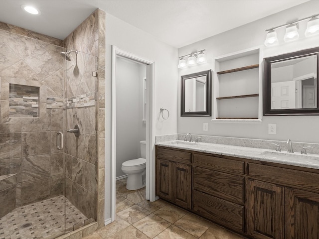 bathroom with a stall shower, toilet, and double vanity