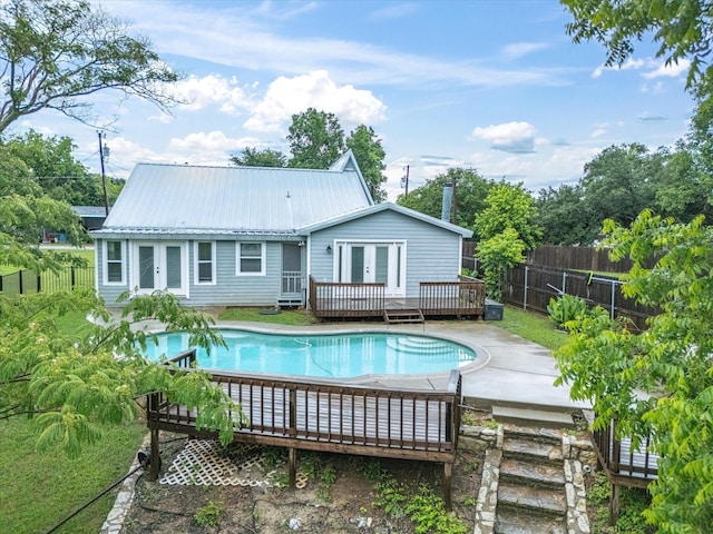 back of house with french doors, a deck, a fenced backyard, and metal roof