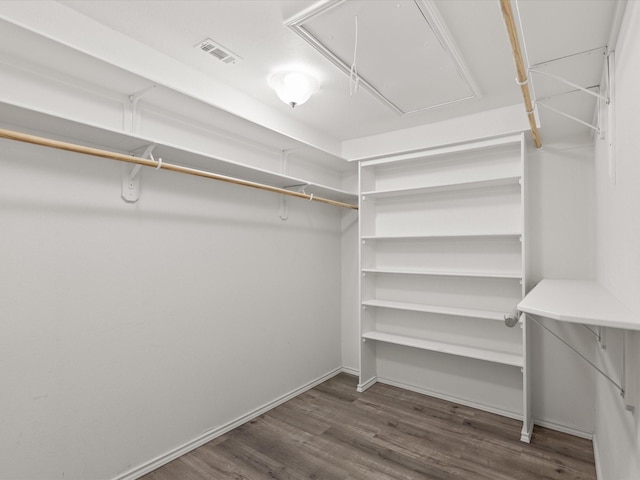 walk in closet with attic access and wood finished floors