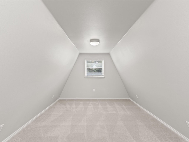 bonus room featuring light carpet, vaulted ceiling, and baseboards