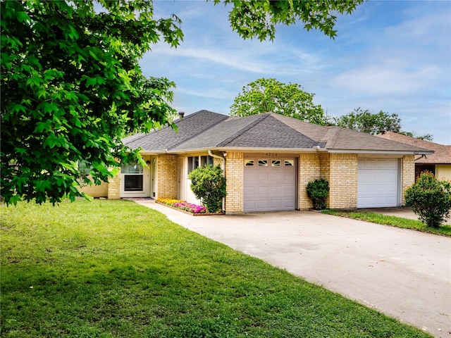 single story home featuring an attached garage, a front yard, concrete driveway, brick siding, and roof with shingles