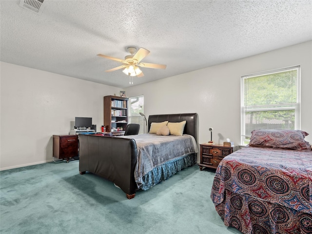 carpeted bedroom featuring a textured ceiling, ceiling fan, and an office area