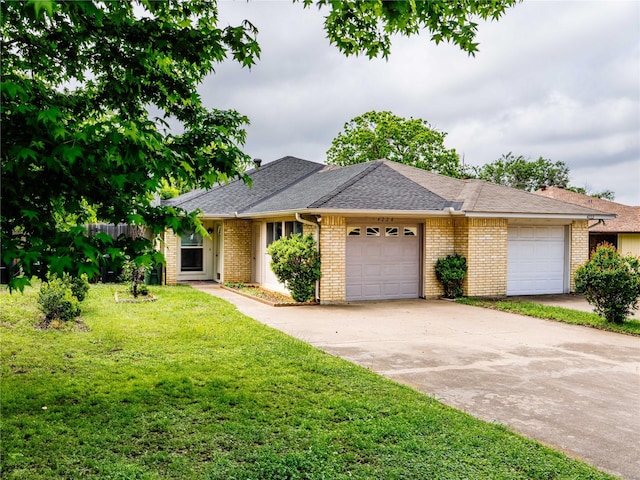 ranch-style home featuring an attached garage, a front yard, concrete driveway, brick siding, and roof with shingles