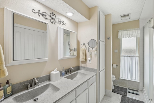 5008 Caliente Dr, Arlington, TX 76017 - full bathroom with toilet, tile patterned flooring, double vanity, and a textured ceiling