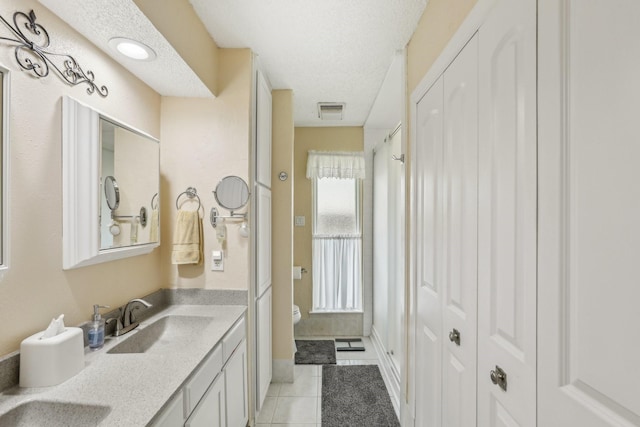 5008 Caliente Dr, Arlington, TX 76017 - bathroom with toilet, tile patterned flooring, double vanity, a closet, and a textured ceiling