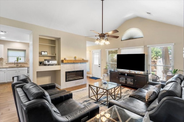 2098 Amber Ct, Lewisville, TX 75067 - living area with light wood finished floors, a ceiling fan, vaulted ceiling, a fireplace, and built in features