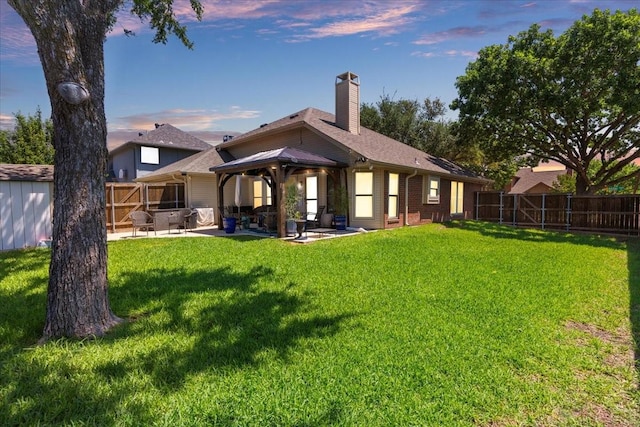 2098 Amber Ct, Lewisville, TX 75067 - back of property at dusk featuring a gazebo, a patio area, a chimney, and brick siding