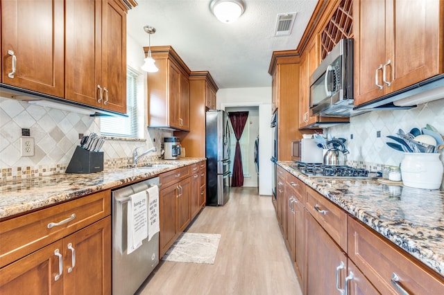1513 Silverleaf Dr, Carrollton, TX 75007 - kitchen with stainless steel appliances, brown cabinetry, light wood-type flooring, decorative backsplash, and a sink