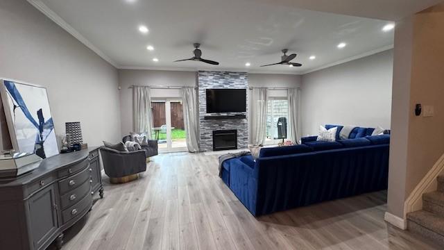 living area with crown molding, a large fireplace, light wood-style flooring, ceiling fan, and recessed lighting