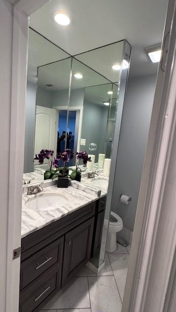 bathroom featuring toilet, vanity, marble look tiles, and recessed lighting