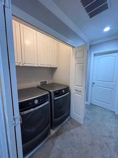 laundry room with cabinet space, washing machine and dryer, carpet floors, and crown molding