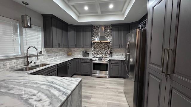 kitchen with appliances with stainless steel finishes, wall chimney exhaust hood, gray cabinetry, a sink, and light wood finished floors