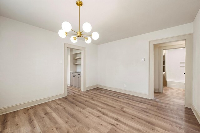 unfurnished dining area with a chandelier, light wood finished floors, and baseboards