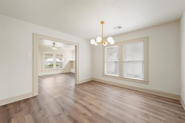 unfurnished dining area featuring light wood-type flooring, a chandelier, and baseboards