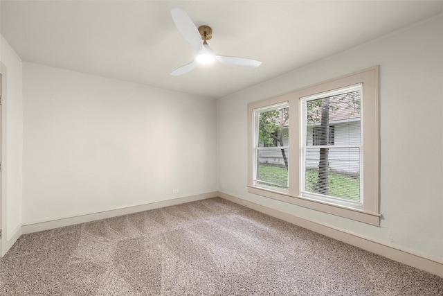 spare room featuring light colored carpet, baseboards, and a ceiling fan