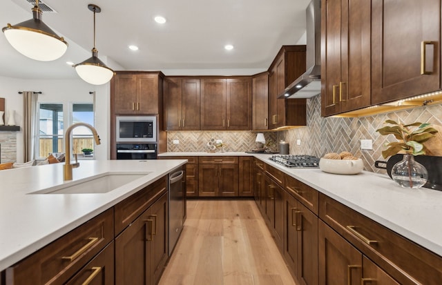 2824 Tophill Dr, Celina, TX 75009 - kitchen with wall chimney exhaust hood, a sink, appliances with stainless steel finishes, light wood finished floors, and light countertops