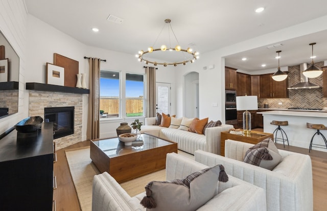 2824 Tophill Dr, Celina, TX 75009 - living room featuring a fireplace, arched walkways, wood finished floors, recessed lighting, and a chandelier
