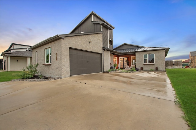 view of front facade featuring brick siding, an attached garage, concrete driveway, board and batten siding, and a front yard