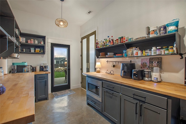 bar with stainless steel microwave, finished concrete floors, and hanging light fixtures