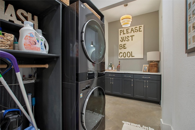 clothes washing area with stacked washer / drying machine and cabinet space