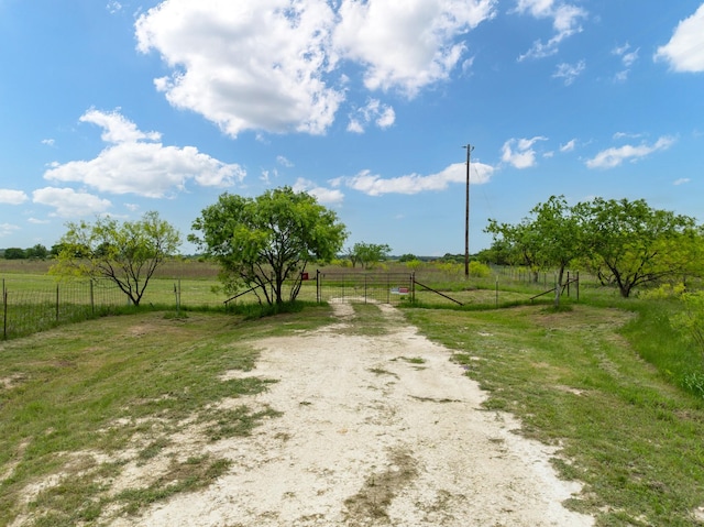 view of dirt / gravel road featuring a view of rural / pastoral area and a gate