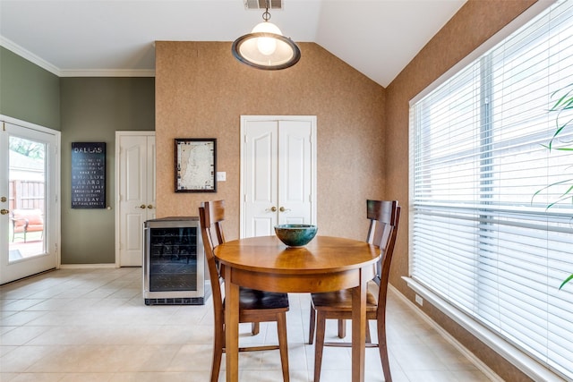 dining room featuring beverage cooler, lofted ceiling, light tile patterned floors, baseboards, and crown molding